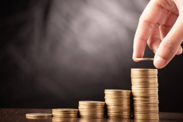 saving money concept hand putting coin on stack